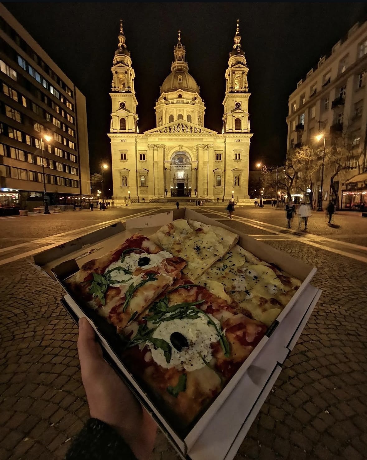 Pizzica pizzaszeletek egy dobozban a Szent István-bazilika előtt éjjel